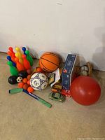 Wide view of toys including colorful bowling pins, basketball, football, soccer ball, and red exercise ball alongside various boxed games and puzzles