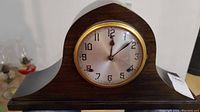 Front view of vintage Wm Gilbert mantel clock showing the wooden curved case, silver face with black numbers, and gold-tone bezel.