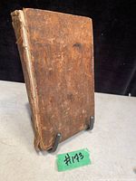 Front cover of antique book showing heavily worn brown leather and damaged spine.