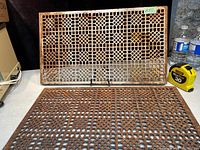 Pair of antique cast iron grates displayed on a table showing front and top views.