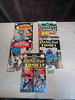 Photo showing 5 pulp-style Batman comic books from DC Comics Detective Comics series laid out in two rows, front covers visible