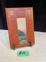 Front cover of antique book 'A Window in Thrums' showing brown cover with gold embossed details and small landscape illustration.