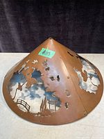 Photo of antique copper lamp shade showing conical shape and scenic cut-outs.