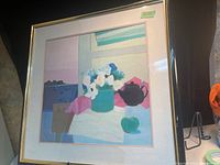 Full view of framed print showing a floral vase, teapot, and apple on a table with colorful background.