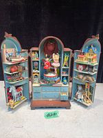 Front view of toy box with all doors open showing multiple toys and detailed figurines such as toy soldier, ballerina, horse, toy boat, train, teddy bear, clown, croquet set, and books.