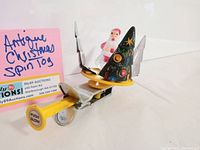 Photo showing the full side view of the antique Christmas push spin toy with Santa and tree, highlighting 'Push Slow' label on the yellow push handle and painted decorations.