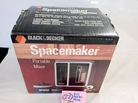 Front and side view of original Black & Decker Spacemaker Portable Mixer SPM50 box showing product name, branding, features, and illustration of the mixer and storage unit.