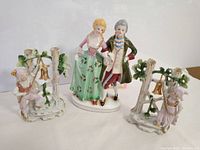 Three porcelain figurines on a white background showing detail and placement in group