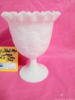 Side angle photo showing full shape of the ruffled edge milk glass vase and footed base.