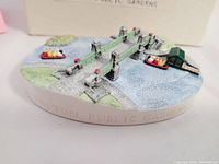 Front angled view of the oval-shaped miniature showing bridge, rowboats, water, grass, and red lamp posts.