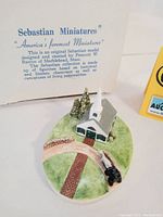 Front view of the signed Sebastian Miniatures Country Church figurine with original informational card in background.