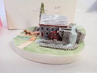 Front angled view of the stone grist mill miniature showing the water wheel, waterfall, and horse with cart on a green base with path