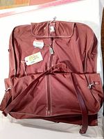 Full view of the maroon garment bag including shoulder strap and external compartments.