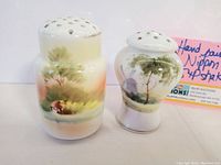 Two vintage Nippon hand painted salt and pepper shakers shown from the front with a pink handwritten note in background.