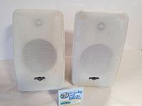 Front view of two white vintage Polk Audio M2 speakers showing perforated metal grilles and logos.
