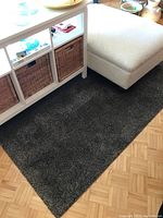 Gray IKEA Adum area rug placed under furniture, showing clean edges and textured synthetic fibers.