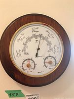 Front view of round wooden framed barometer showing main dial and two smaller dials for temperature and humidity, with a 9.5 inch diameter label.