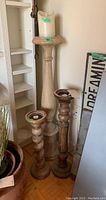 Photo showing all three candlestick holders and the faux battery candle together, placed upright on the floor near shelving and wall.