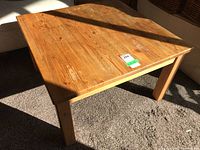 Square wood coffee table angled view showing wood grain and surface wear on top.