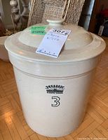 Front angle view of off-white ceramic crock with lid, showing stamped logo and number 3.