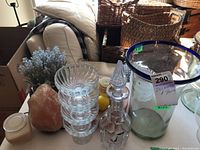 Cut glass decanter, stacked clear bowls, salt lamp candle, faux plant, large glass vase