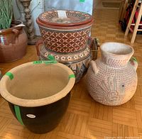 Photo shows four ceramic items: large two-handled planter, smaller two-handled indigenous-style planter with birds, dark blue planter with cracks, and matching decorative ceramic plate stacked together.
