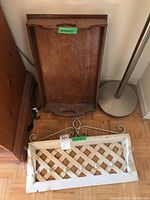 Wooden tray leaning against the wall with metal hanging shelf placed in front on floor. Shows condition and relative size of items.