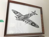 Framed black and white print showing a Supermarine Spitfire aircraft in flight, signed in bottom right corner.
