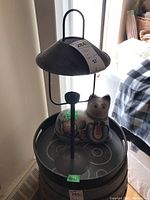 Metal candlestick lamp with round shade and ceramic cat figurine inside the faux leather tray