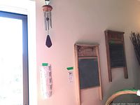 Photo of two vintage wooden washboards with zinc scrubbing surfaces hanging on a wall, and a wood and metal wind chime hanging nearby.