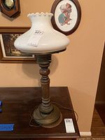 Full view of the lamp showing the wooden and brass base and milk glass shade with scalloped edge.