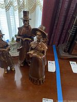 Photo showing four brown-toned carolers family statues, detailed facial features, clothing, and musical instruments.