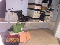 Photo showing multiple purses including white wicker, black beaded wooden purse, green leather handbag, patchwork leather purse, and pink purses along with stacked shoe boxes.