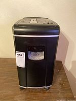 Front view of black Ativa MDM 8000 shredder with clear window showing shredded contents and auction lot number attached.