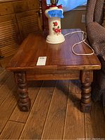 Photo showing the top and side view of the wood side table with scratches and a lamp on top.