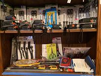 Hand tools including clamps and wire brushes stored on wooden shelves.