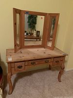 Full view of wooden vanity with tri-fold mirror and three drawers, showing overall design and condition.