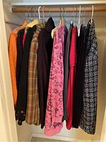Hanging women's clothes including jackets, sweaters, and tops in various colors and patterns