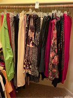 Photo of women's clothing on hangers showing various pants, skirts, and tops in different colors and patterns