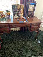 Front view of wooden desk showing the surface, drawers, and items placed on top.