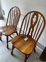 Pair of oak wooden chairs with spindle backs and classic turned legs shown from front angle