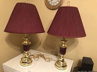 Pair of touch lamps with burgundy shades and gold and burgundy bases, showing cords and top finials