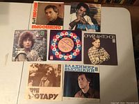 Seven 45 rpm vinyl records arranged on table, featuring Russian and one Spanish title. Shows front covers of all records.
