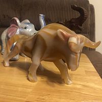 Photo showing carved onyx bull front and side view with ceramic elephant and wooden elephant behind