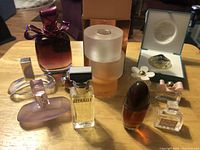 Full view of the 11 perfume bottles arranged on a wooden surface, showing various shapes, sizes and partial fill levels