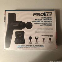 Photo of the sealed box front showing the PROfit Percussion Muscle Massager and details about weight, usage time, speed settings, and included attachments.