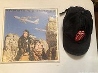 Vinyl record and black hat with red tongue Rolling Stones logo front view