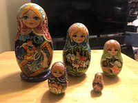 Full set of 5 Matryoshka dolls displayed in size order, showing hand-painted details and color variations on wooden dolls.