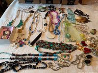 Overview photo showing the entire collection of assorted costume jewelry spread out on a bed including bead necklaces, earrings, and bracelets