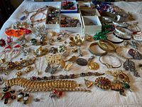 Wide view of assorted costume jewelry including bracelets, necklaces, pins, earrings displayed on a cloth surface